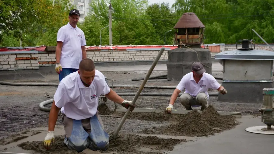 Equipo de aplicadores extendiendo mortero impermeable sobre una azotea